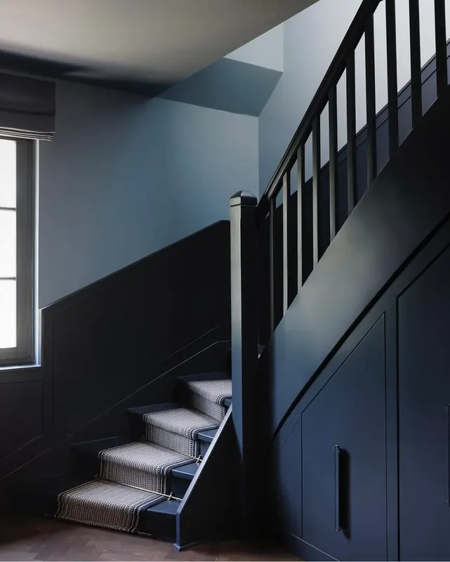 Treppenhaus mit dunkel lackierter Treppe und Wandvertäfelung