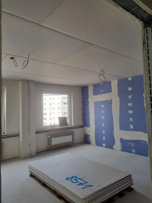 Neue Trennwand mit blauen Schallschutzplatten, frisch gespachtelt